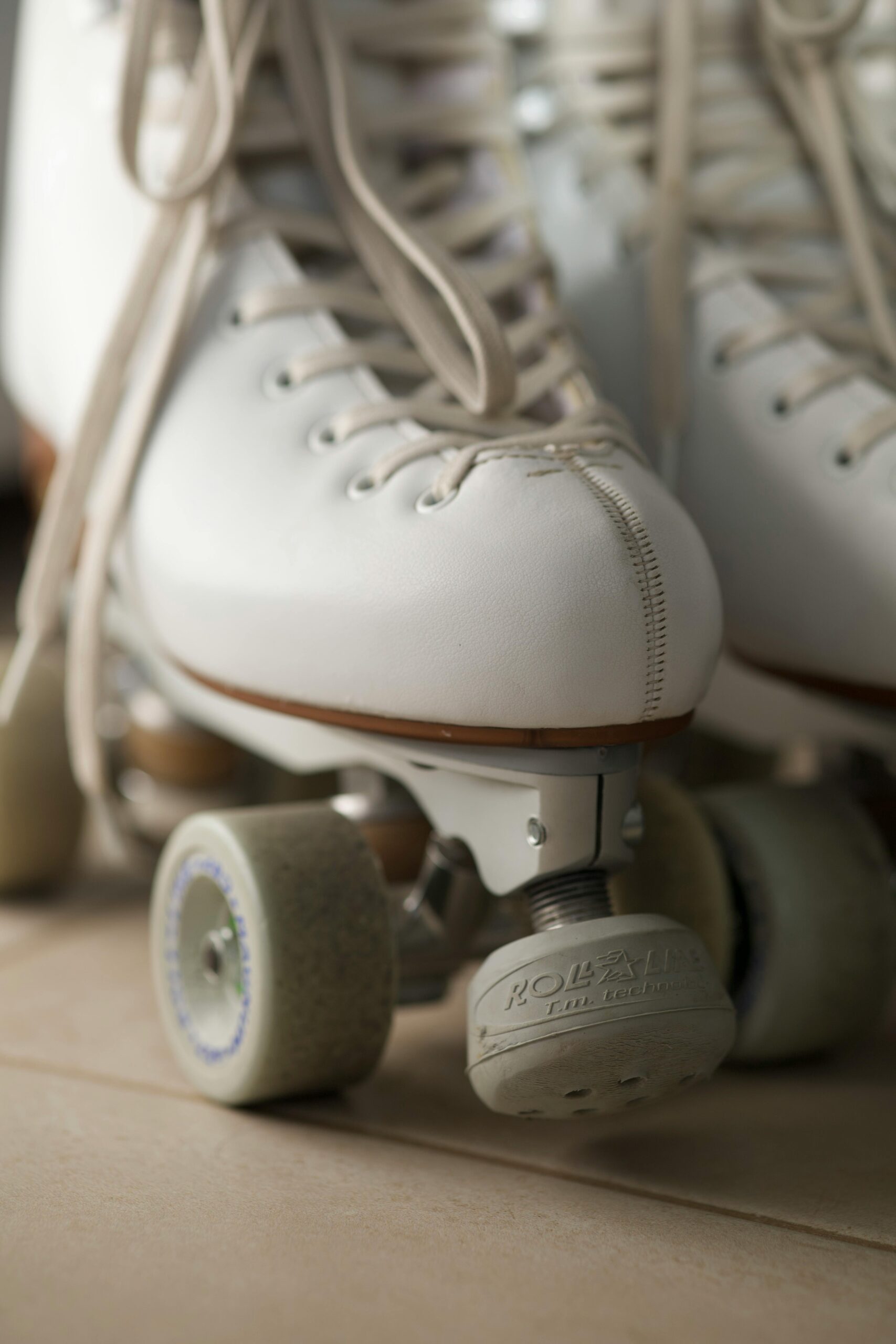 Detailed image of vintage white roller skates with laces and wheels visible.